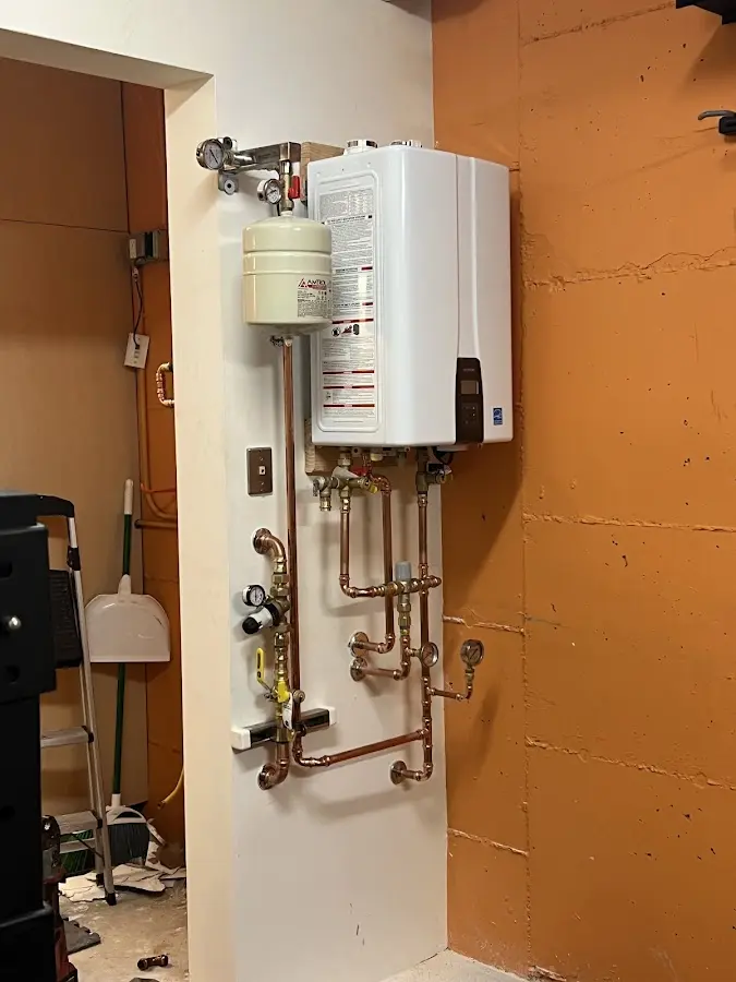 Plumbing technician inspecting water heater connections in Harrisville